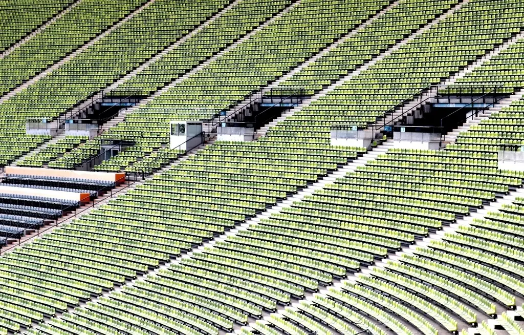 Vista cenital de miles de asientos verdes vacíos organizados en filas curvas