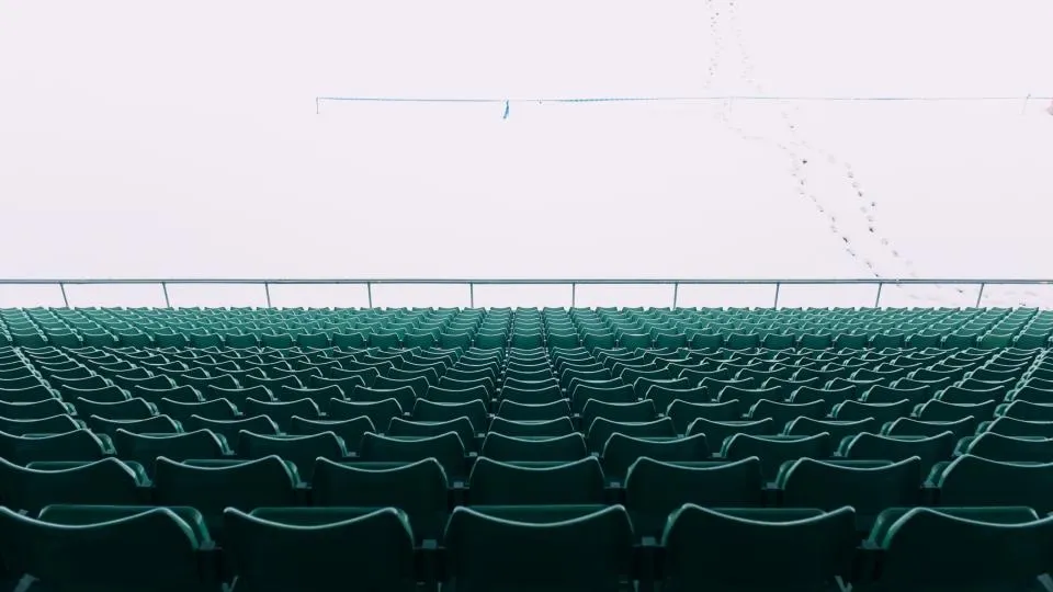 Hileras de asientos verdes de una tribuna vacía bajo un cielo claro