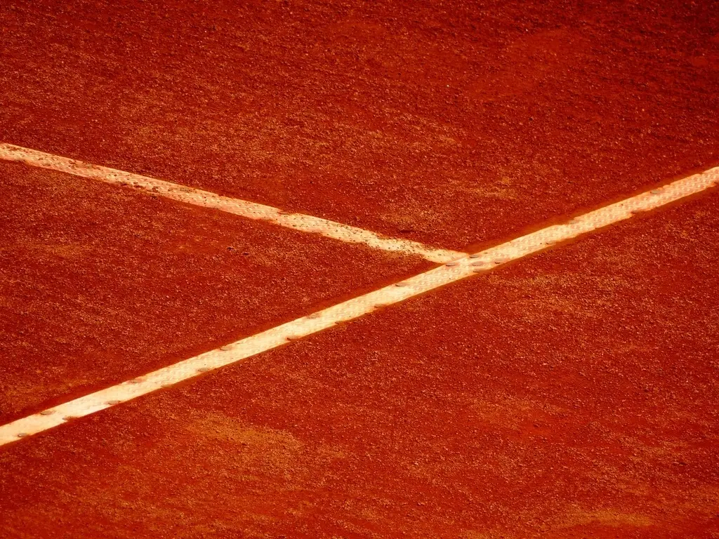 Primer plano de dos líneas blancas que se cruzan sobre una superficie de tierra batida
